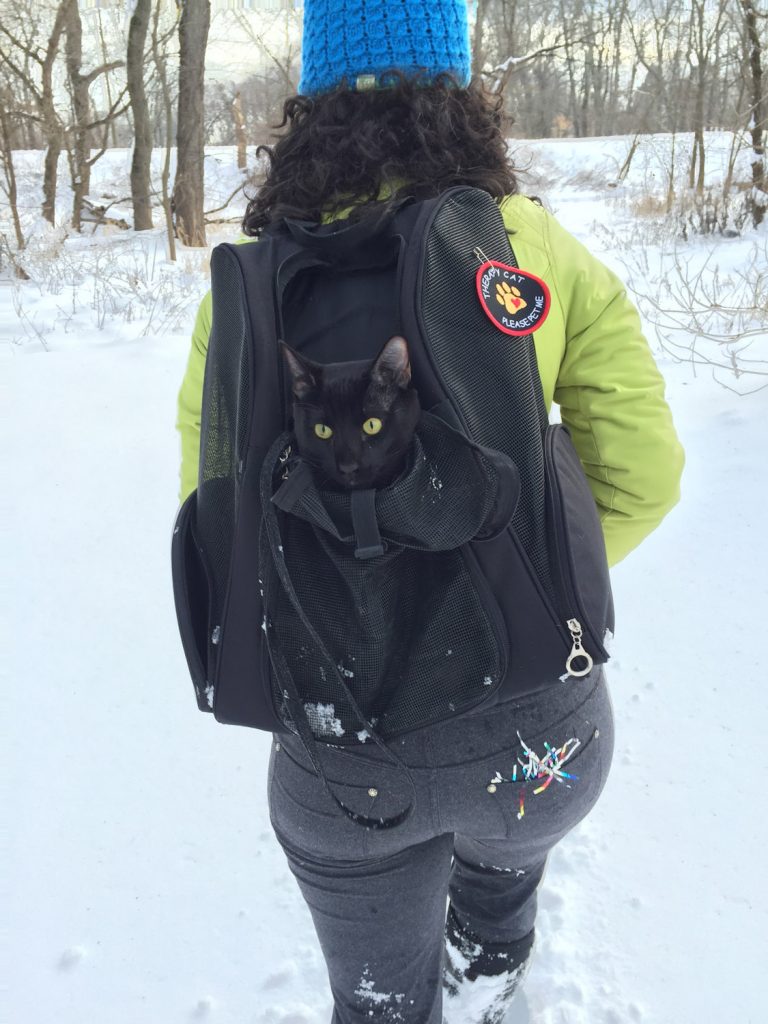 woman hiking with cat in backpack