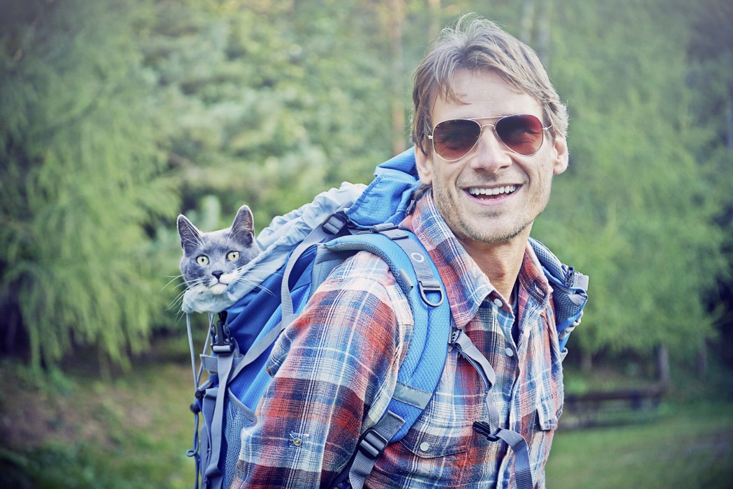 man hiking with cat in backpack