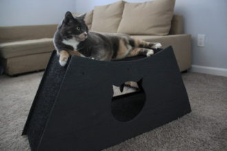 cat lying on top of homemade cat cave